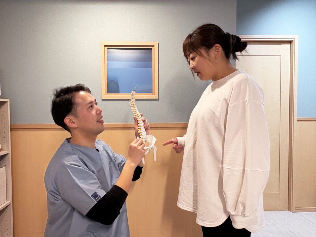 鹿児島市の整体院かごしま整体心晴｜理学療法士が背骨の模型を使って体の状態を説明している様子