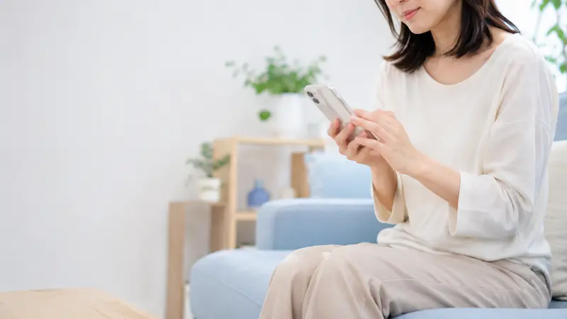 スマートフォンから整体院へ予約や相談のメッセージを送る女性